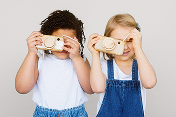 two kids taking photo using a camera